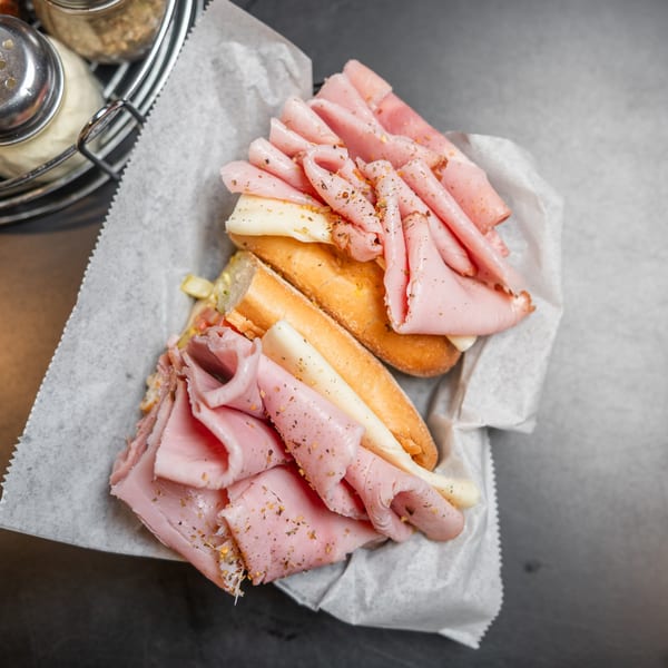 Overhead view of a ham and cheese sub sandwich in a paper-lined basket.