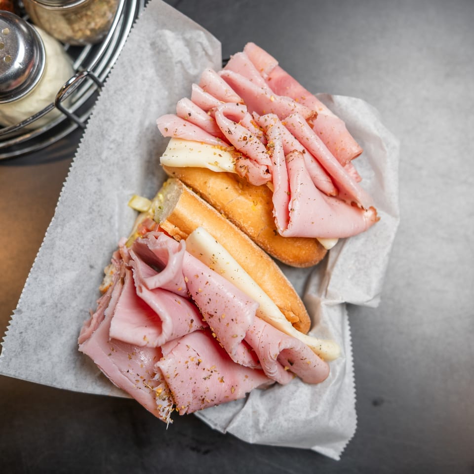 Overhead view of a ham and cheese sub sandwich in a paper-lined basket.